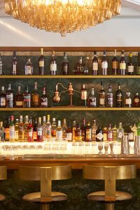 Complementary bar shelving and bar stool backs in Double Stone Steel PVD colored stainless steel Brass Brush