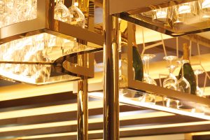 Detail of overhead bar rack in the Brasserie created from V-Grooved Double Stone Steel colored stainless steel Champagne Mirror PVD. - The Devonshire Club Hotel, London, UK - Interior Design: March & White