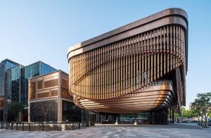 The detailed façade of the Shanghai Bund Arts and Cultural Centre in context with the more boxy style of surrounding buildings. Architectural detailing fabricated from PVD stainless steel in Rose Gold Vibration. - Architects: Foster & Partners; Heatherwick Studio - PVD: Double Stone Steel in partnership with John Desmond Ltd