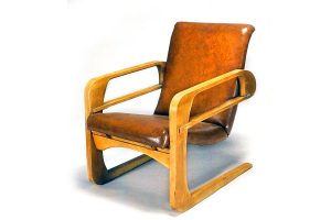 Airline chair with wooden frame and caramel-colored Naugahyde cushions. It was designed by Kem Weber in the 1930s and supplied to the newly-built Walt Disney studios.
