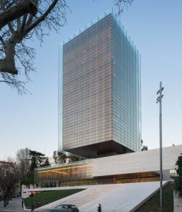 Castelar Building Architects: Rafael de la Hoz Arderius and Gerardo Olivares. Access to the building from Paseo de la Castellana, the glass and steel lantern appears as a floating object over the travertine podium. Photography by Duccio Malagamba