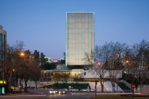 Castelar Building. Architects: Rafael de la Hoz Arderius and Gerardo Olivares. Front elevation at sunset time from Paseo de la Castellana, the building resembles a minimalist sculpture. The abstract glass volume presents as a pure geometric form devoid of scale on which we hardly appreciate the different floors contained. Photography by Duccio Malagamba